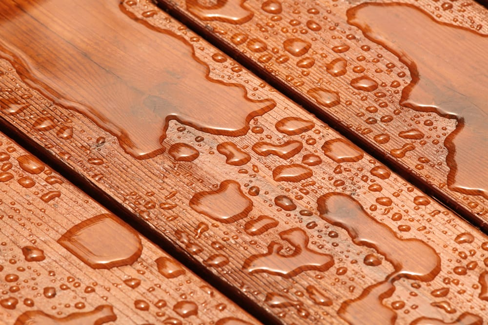 Close-up of water droplets on a wooden surface, showcasing the texture and grain of the wood.