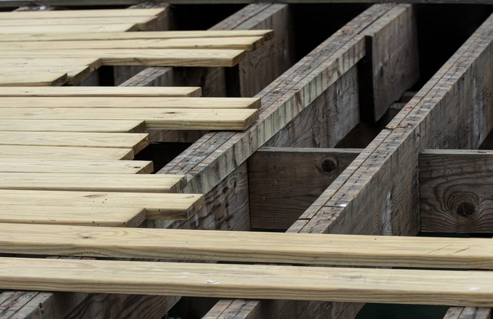 Wooden planks and beams are laid out in a partially constructed deck framework.